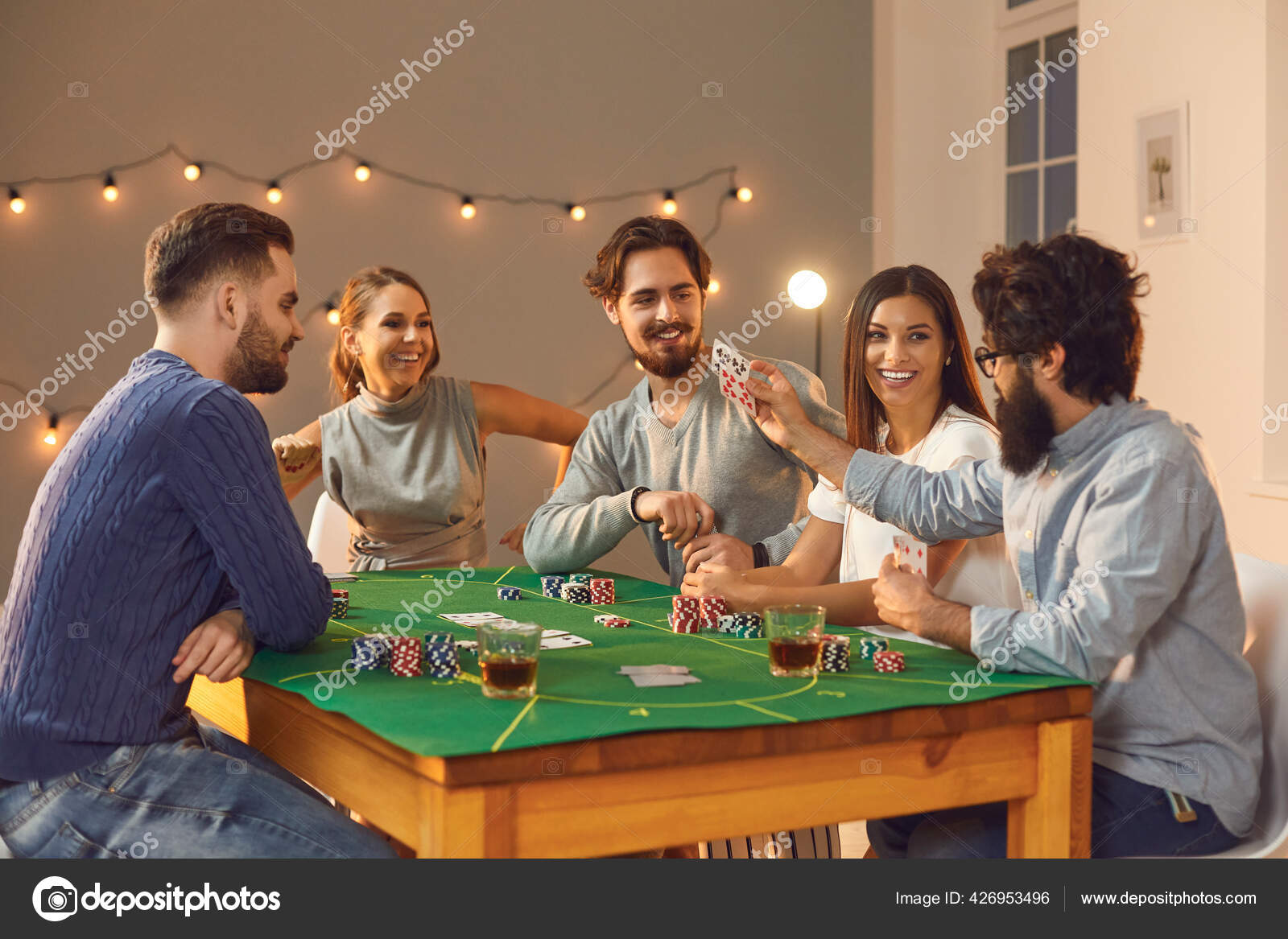 Grupo de amigos alegres apostando, bebendo e jogando poker na mesa em casa  fotos, imagens de © lacheev #426953496